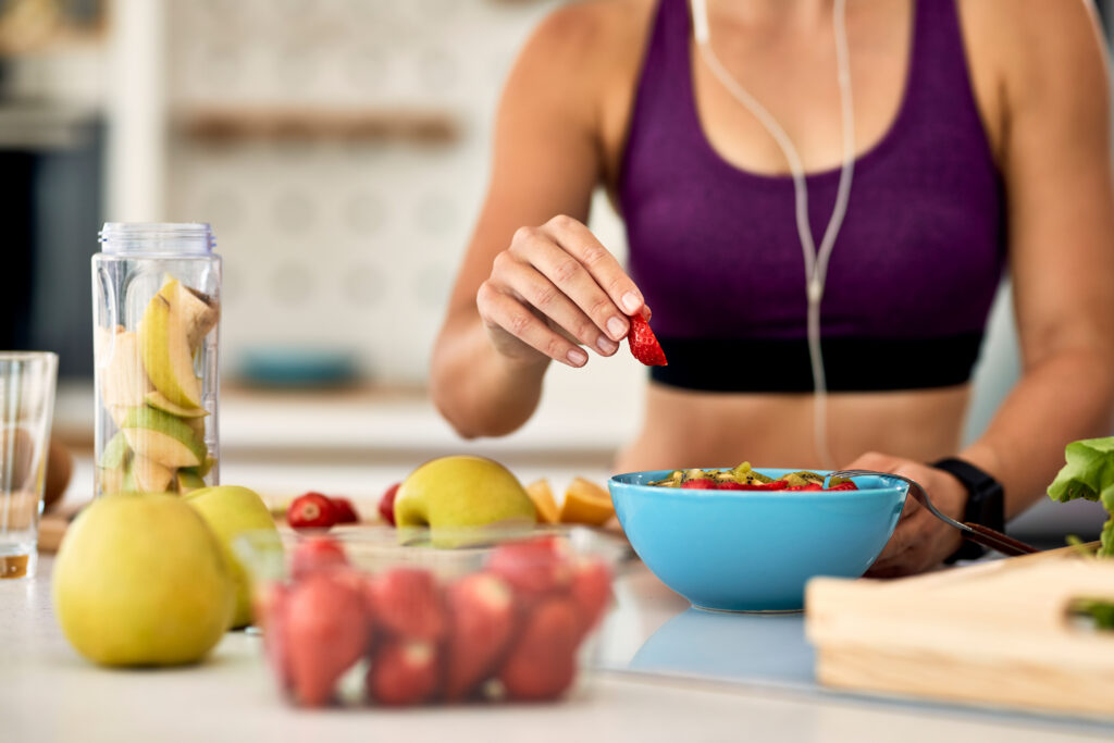 Femme sportive qui fait sa salade de fruit